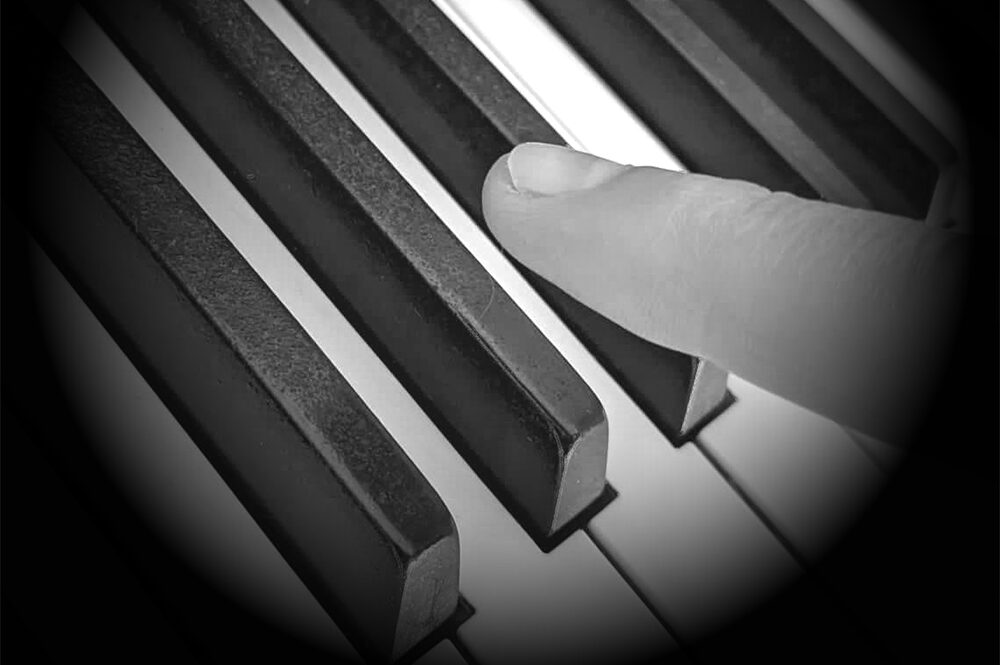 a finger hovering over a piano key
