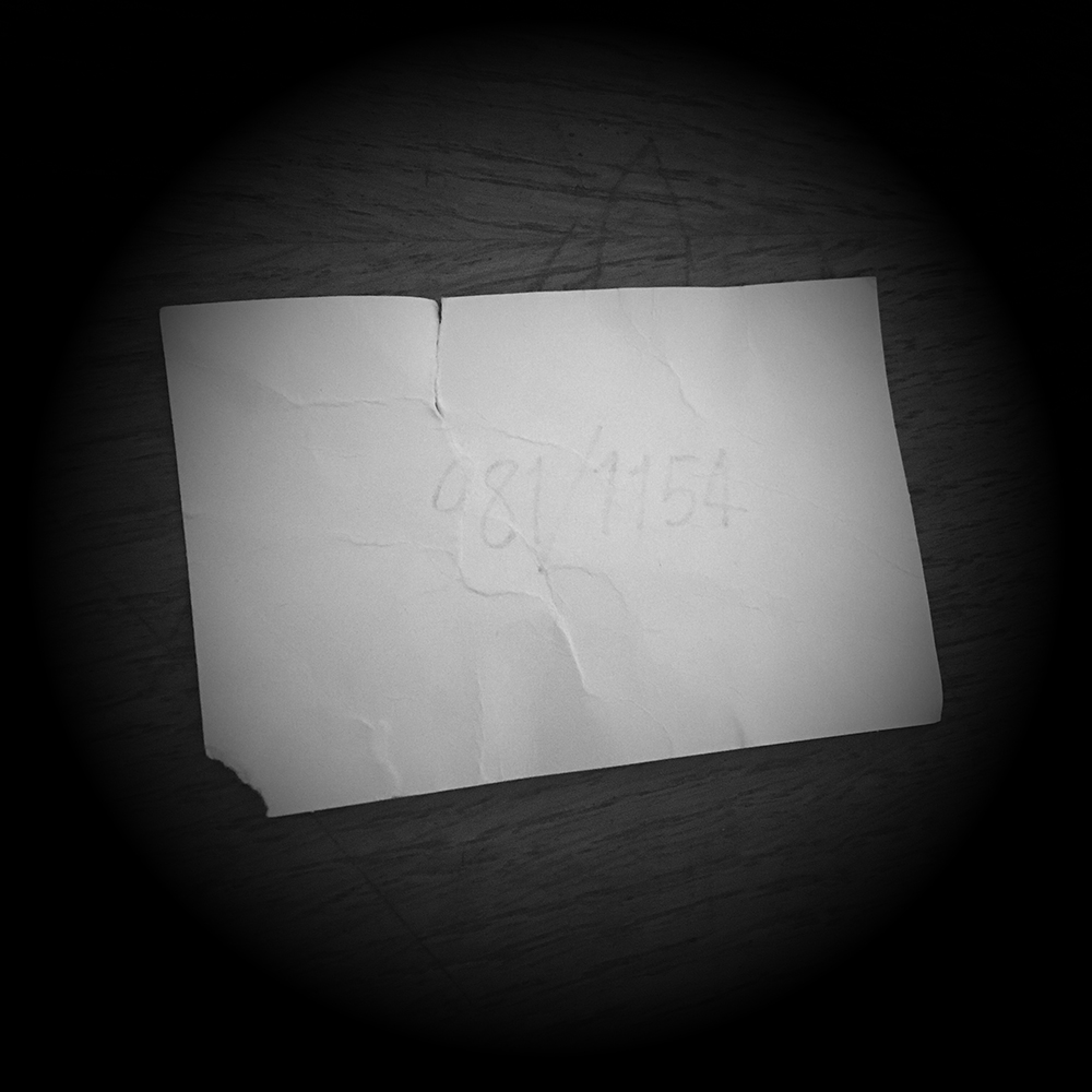 A small, old crumpled card with the number 981/1154 written on it in very faint pencil